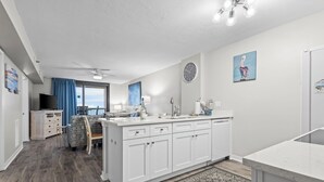 Une cuisine moderne avec des meubles blancs, un grand îlot central et une vue sur la salle à manger.