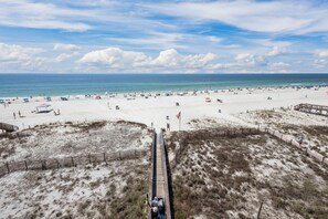 A beach with a wooden boardwalk leading to the shore, sandy dunes, and a clear view of the ocean.
