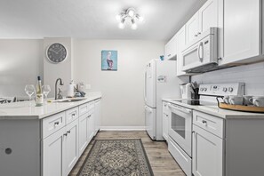 A modern kitchen with white cabinetry, a built-in oven, a microwave, and a refrigerator. - Incredible Ocean Front Views, Indoor/Outdoor Pool, Hot Tub, Fully Stocked, 4 TVs (Orange Beach)
