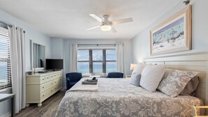 Une chambre à coucher avec un lit, une télévision, une commode et un ventilateur de plafond.