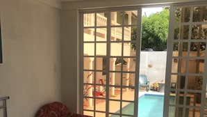 Une chambre avec un lit, une chaise et une vue sur une piscine extérieure, visible à travers une porte vitrée.