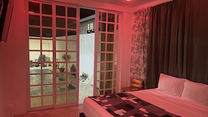Une chambre à coucher avec un lit, une porte-fenêtre coulissante donnant sur un balcon et un luminaire au plafond.