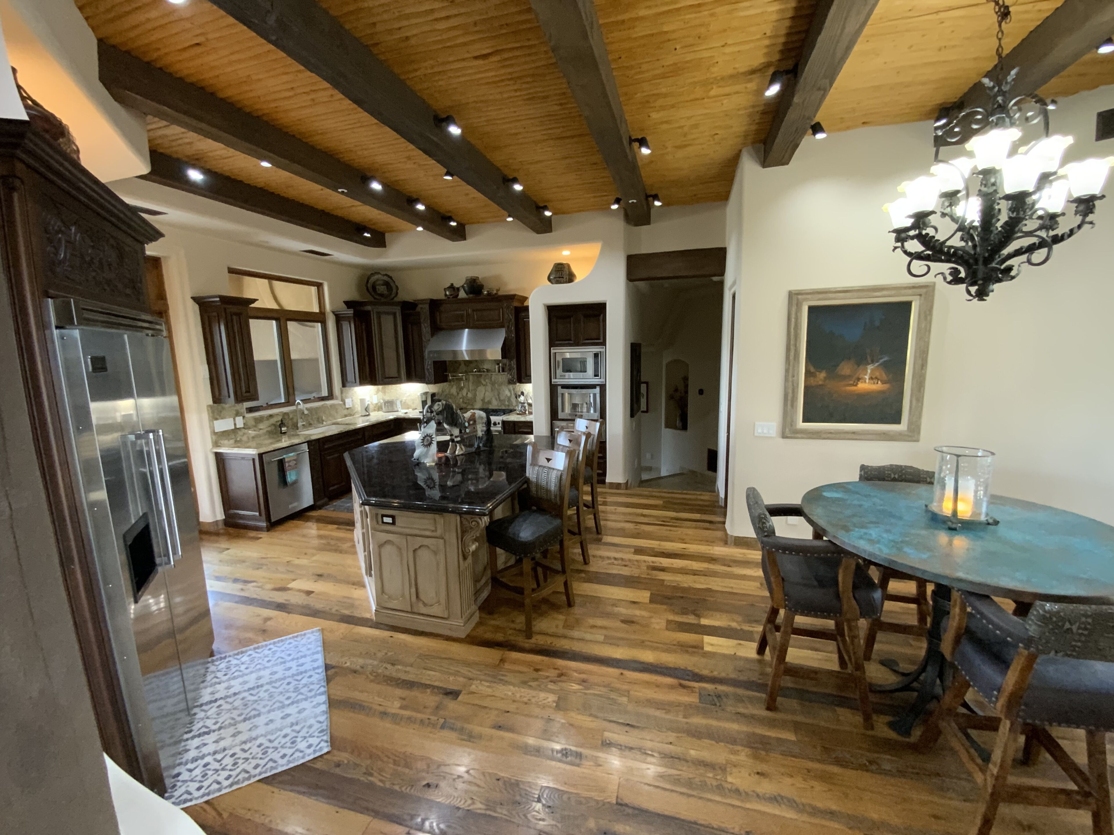 Una cocina amplia con armarios de madera oscura, una isla central y un comedor con una mesa redonda y sillas.