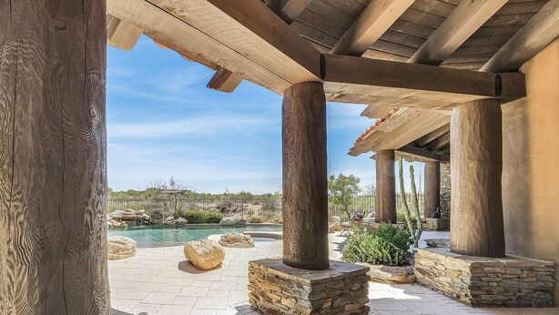 A covered outdoor area with stone pillars, a pool, and a view of a desert landscape. - Sonoran Desert Retreat - Quiet, Gated, Custom home with Incredible SUNSETS ! (Scottsdale)