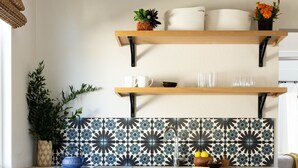 Eine Küche mit weißen Schränken, einer Holz Arbeitsplatte und einer Rückwand mit einem floralen Muster.