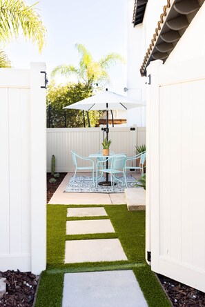 A patio area with a white fence, a table with chairs, and an umbrella.