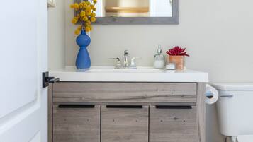 A bathroom with a white sink, wooden cabinet, and a mirror above it.