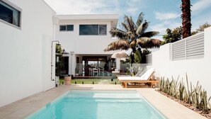 A modern house with a swimming pool, a patio with lounge chairs, and a view of the backyard. - 6 bedrooms, ocean views, pool & spa (Cronulla)