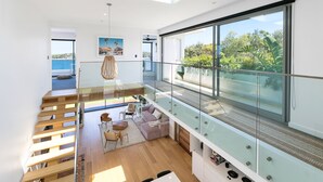 A modern interior with a glass balustrade, wooden staircase, and a view of the sea. - 6 bedrooms, ocean views, pool & spa (Cronulla)