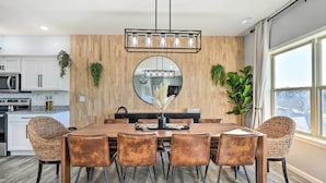 A dining area with a wooden wall, a round mirror, and a hanging light fixture. - Reeds Spring Condo ~ 3 Mi to Silver Dollar City! (Reeds Spring)