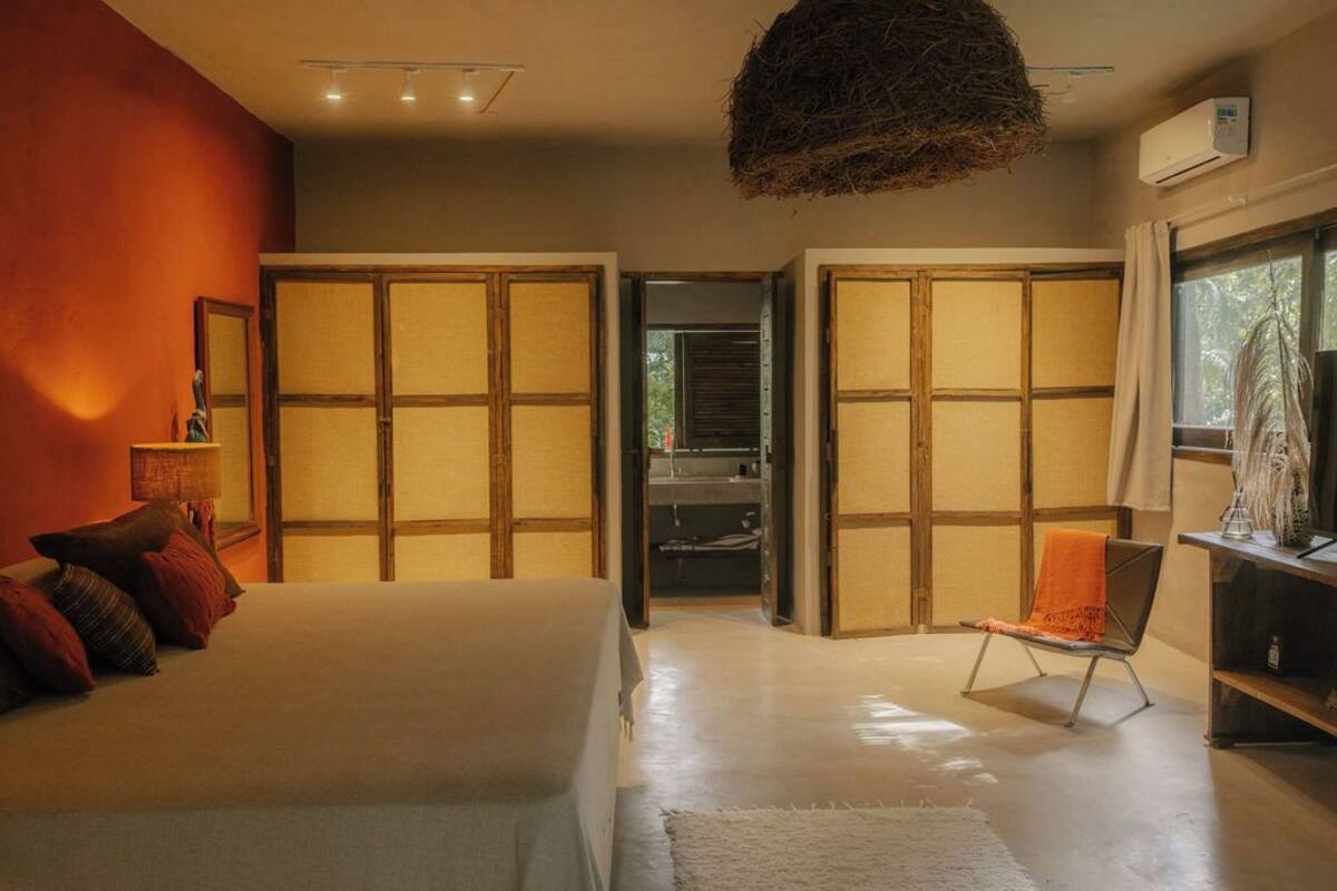 A modern bedroom with a large bed, a chair, and a hanging light fixture.