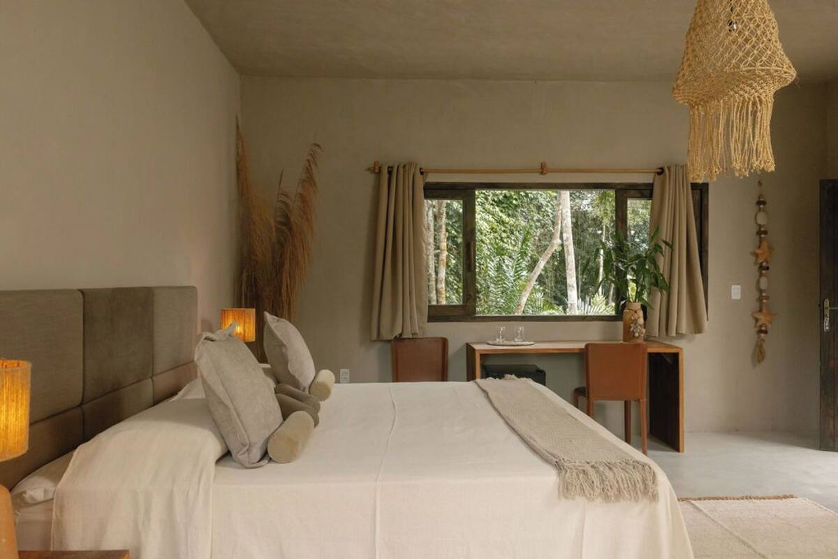 A bedroom with a bed, bedside lamps, a desk, and a window with curtains.