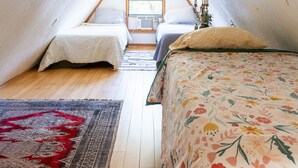 A dorm-style room with two beds, a window, a lamp, and a rug. - The Library - A Hill Country Cottage (San Marcos)