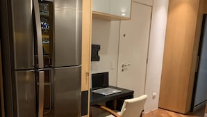 Een moderne keuken met een roestvrijstalen koelkast, een houten eettafel met een stoel, en witte kasten.