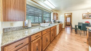 A kitchen with wooden cabinets, a granite countertop, and a window with blinds. - Ruidoso Vacation Rental Home: 15 Mi to Ski Apache (Ruidoso)