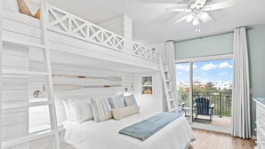 A bedroom with a bunk bed, a balcony with a chair, and a view of the city. - Whispering Palms Seacrest (Panama City Beach)