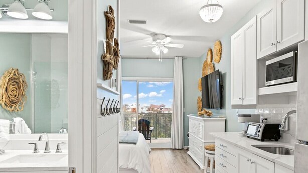 A modern kitchen with white cabinets, a microwave, and a toaster. - Whispering Palms Seacrest (Panama City Beach)
