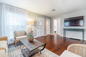 A living room with a wooden coffee table, a sofa, a TV mounted on the wall, and a fireplace.