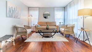 Ein modernes Wohnzimmer mit einer Couch, zwei Sesseln, einem Couchtisch und einer Lampe.