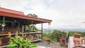 A wooden deck with outdoor seating and a view of a cityscape. - Buen Camino Hotel, San Mateo (San Mateo)