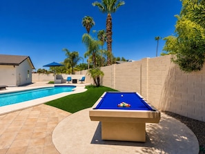 A pool area with a blue pool table, a small building, and palm trees. - Walk to Dining & Shops | 5BR for 12 | Putting Green, Basketball Hoop & Fire Pit (Scottsdale)