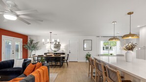 Eine moderne Küche mit weißer Arbeitsplatte, Holzstühlen und Pendelleuchten.