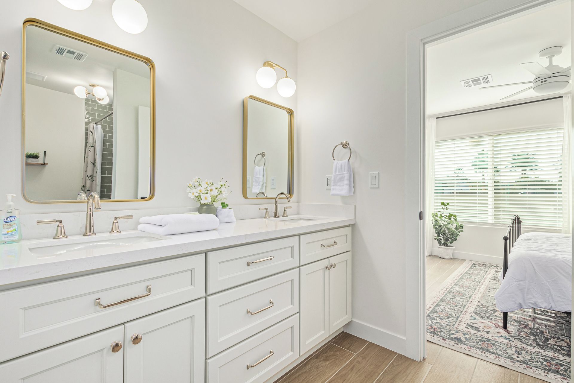 A modern bathroom with dual sinks, a large mirror, and a ceiling fan.