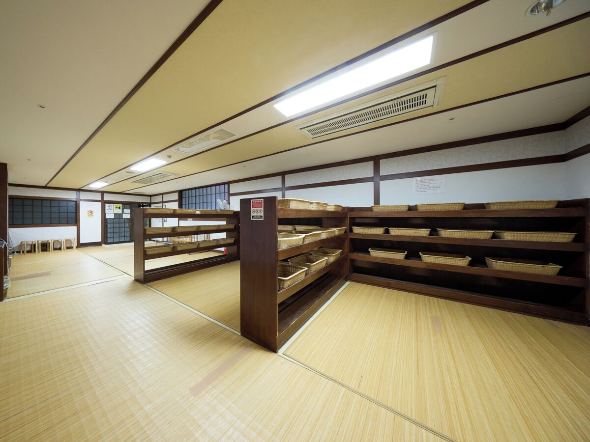 A traditional Japanese room with tatami flooring, wooden shelves with baskets, and a sliding door.