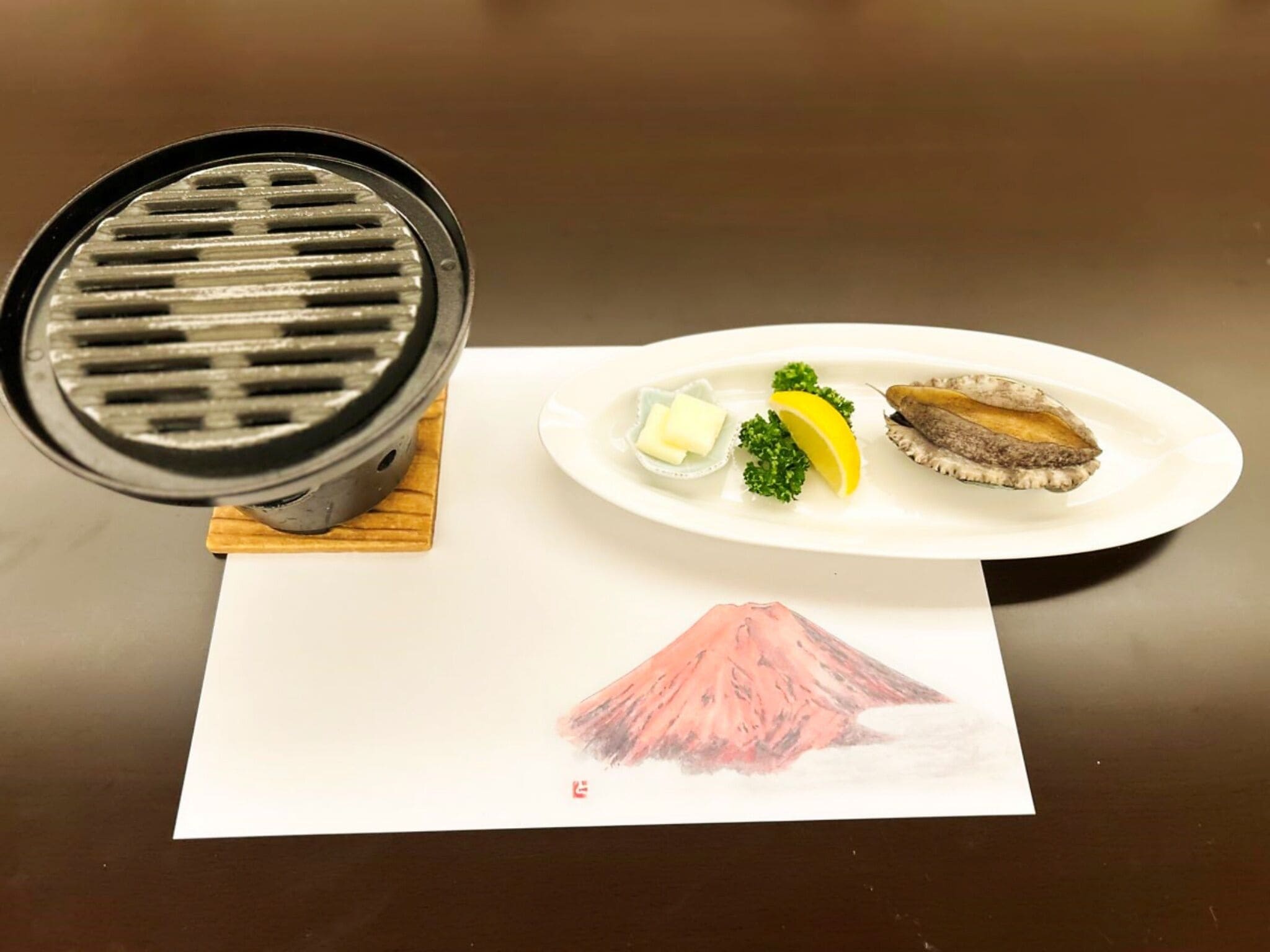 A grill, a plate with food, and a drawing of a mountain.