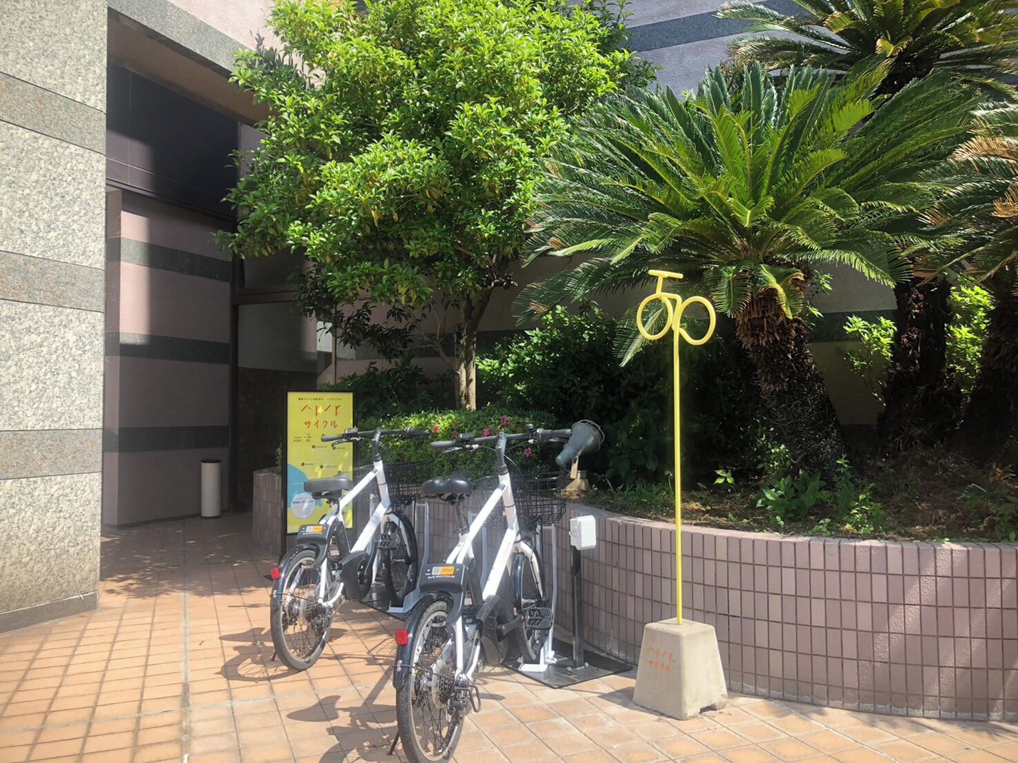 A parking area with bicycles, a sign, and a building entrance.