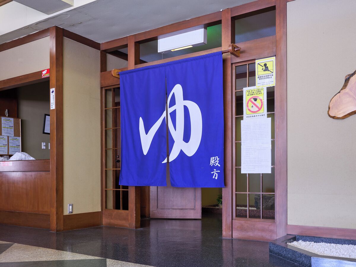 A reception area with a blue banner, wooden reception desk, and a sign with a no-smoking symbol.