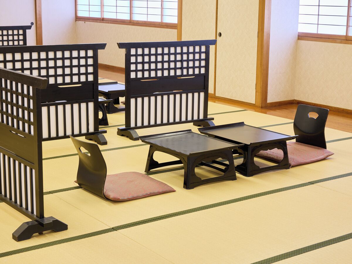 A tatami mat room with traditional Japanese furniture including low tables and cushioned seating.