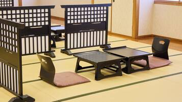 A tatami mat room with traditional Japanese furniture including low tables and cushioned seating.