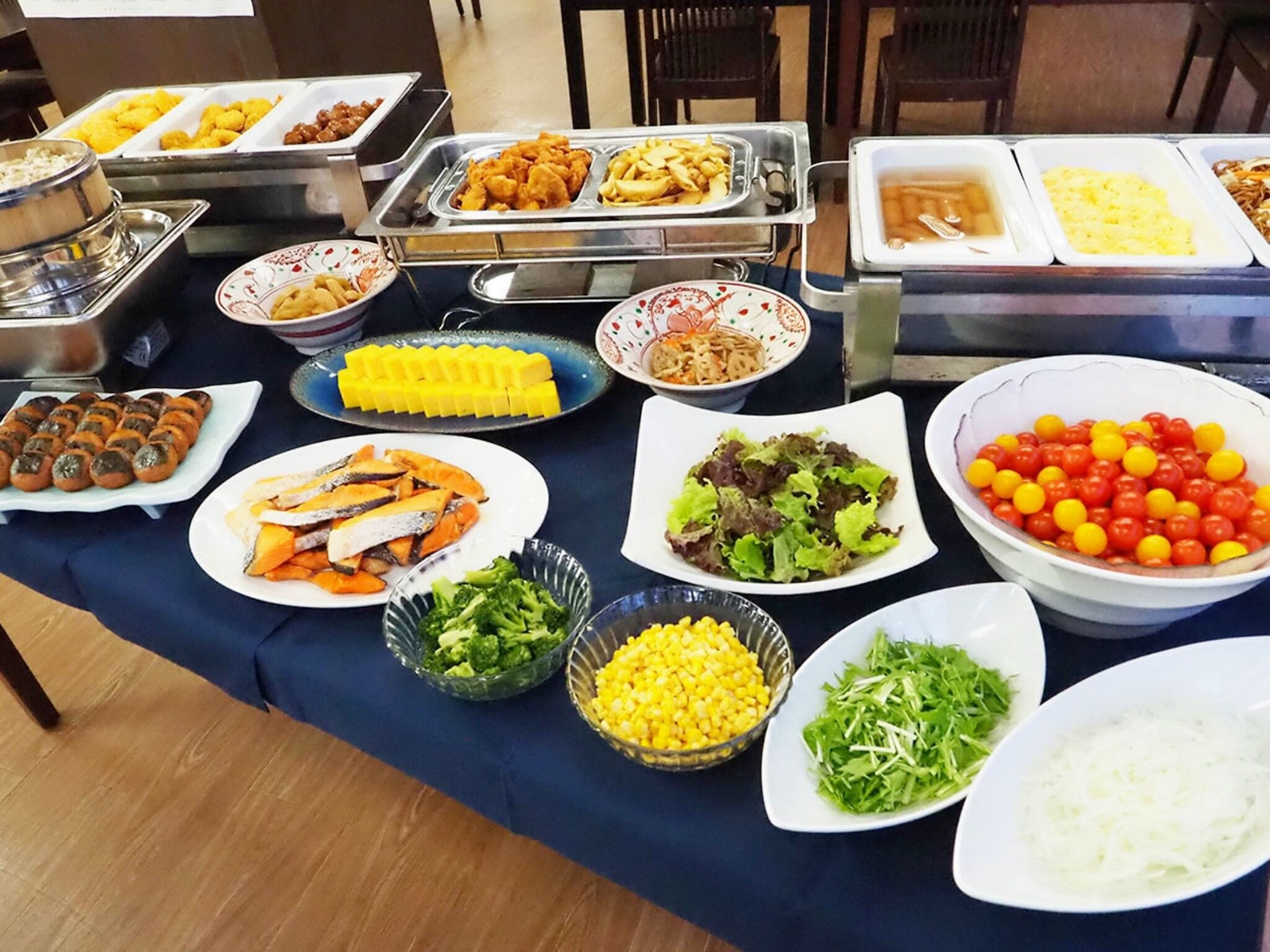 Una mesa de bufé con diversos alimentos, incluyendo ensaladas, frutas y verduras.