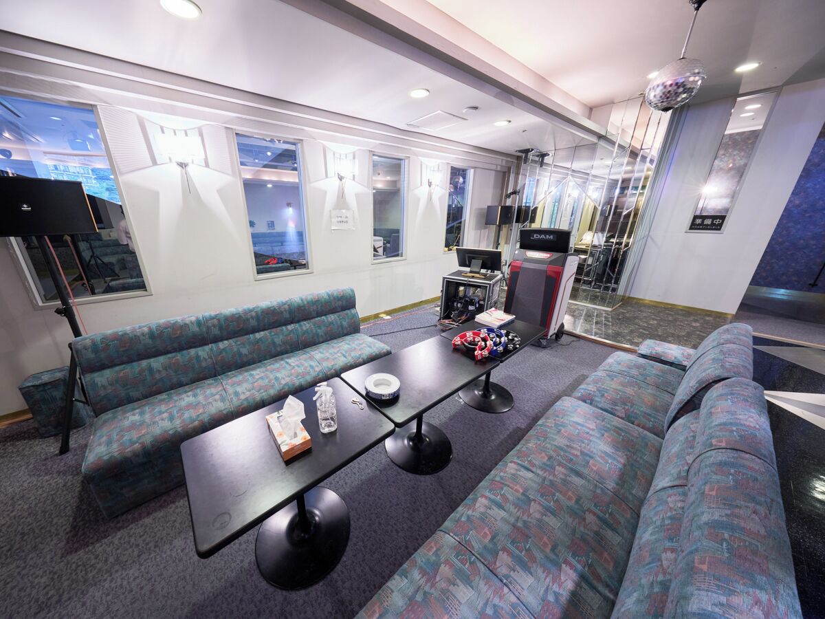 A modern lounge area with patterned seating, a central table, and a television.