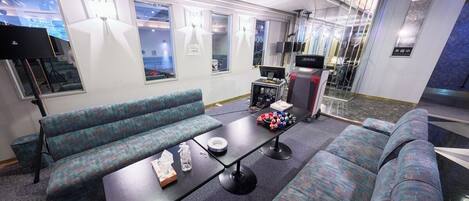 A modern lounge area with patterned seating, a central table, and a television.