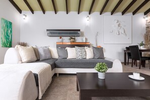 A modern living room with a sectional sofa, a coffee table, and a dining area with chairs and a table.