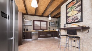 Una cocina moderna con refrigerador de acero inoxidable, armarios de madera, lavavajillas integrado y una zona de bar con taburetes.