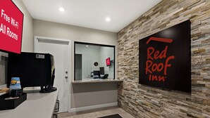 A reception area with a Red Roof Inn sign, a glass door, a counter with a coffee machine, and a sign offering free Wi-Fi in all rooms. - Red Roof Inn Los Angeles - Wilmington, CA (Wilmington)
