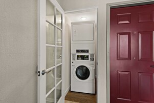 A laundry room with a washing machine and dryer, a door with frosted glass panels, and a red door.