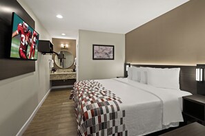 A modern hotel room with a large bed, a TV mounted on the wall, a bathroom with a vanity, and a framed picture on the wall. - Red Roof Inn Los Angeles - Wilmington, CA (Wilmington)