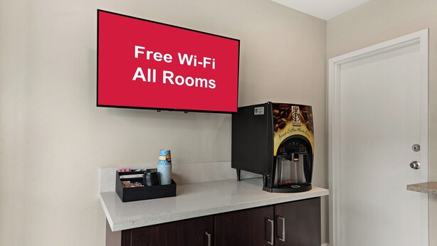 A room with a coffee machine, a stack of cups, and a sign stating "Free Wi-Fi All Rooms". - Red Roof Inn Los Angeles - Wilmington, CA (Wilmington)