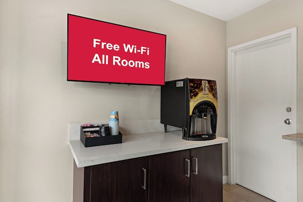 Ein Zimmer mit einer Kaffeemaschine, einer Stapel Tassen und einem Schild mit der Aufschrift 'Free Wi-Fi All Rooms'.