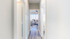A narrow hallway leading to a living area with a sofa and a rug.