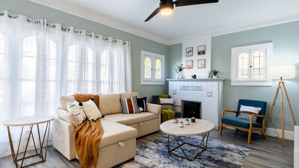 A living room with a beige sofa, a round coffee table, a blue armchair, and a fireplace.