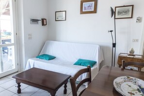 A room with a white sofa, a wooden table, and a dining table with a decorative plate.