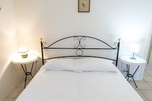 A neatly made bed with white linens, two bedside tables with lamps, and a framed picture on the wall.
