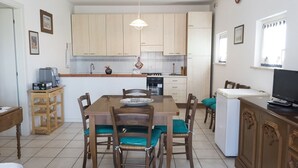 A compact kitchen with wooden cabinets, a dining table with chairs, a refrigerator, and a television on a cabinet. - M310 - Marcelli, three-room apartment with terrace convenient to services (Marcelli)