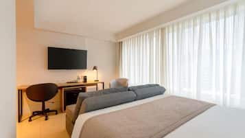 A hotel room with a bed, a desk, a chair, a television, and a window with curtains.