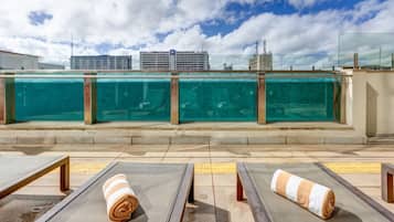Zona de piscina en la azotea con sillones reclinables y vista al horizonte de la ciudad.